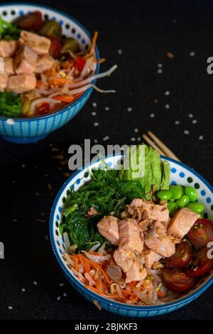 Zwei verschiedene Schalen mit Lachs, Gemüse und Reis. Hawaiianische Pokeküche. Stockfoto