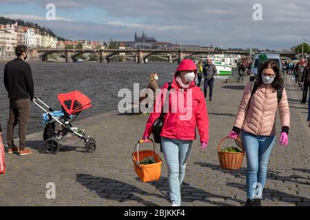 PRAG, TSCHECHISCHE REPUBLIK - 25. APRIL 2020: Frauen tragen Schutzmaske und Handschuhe auf dem Markt Naplavka Bauern, wieder eröffnet zum ersten Mal s Stockfoto