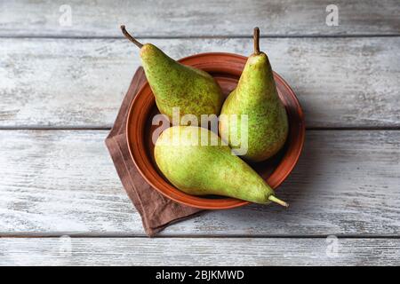 Reife Birnen in Schale auf Holztisch Stockfoto