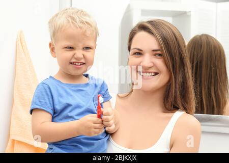 Mutter und niedliches Kind mit Zahnbürste im Badezimmer Stockfoto