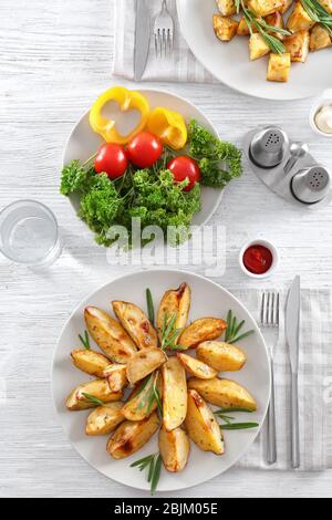 Zusammensetzung mit Teller mit köstlichen Rosmarinkartoffeln auf dem Tisch Stockfoto