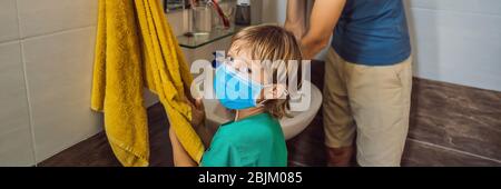 Papa lehrt seinen Sohn, seine Hände richtig zu waschen. Vater und Sohn in medizinischen Masken wegen Coronovirus. Epidemie. Bleib zu Hause. Waschen Sie Ihre Hände BANNER, LANG Stockfoto
