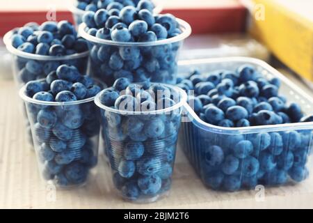 Frische Blaubeeren in Plastikbechern auf dem Markt, Nahaufnahme Stockfoto