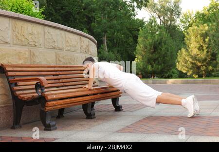 Schöner sportlicher Mann, der Liegestütze im Park macht Stockfoto