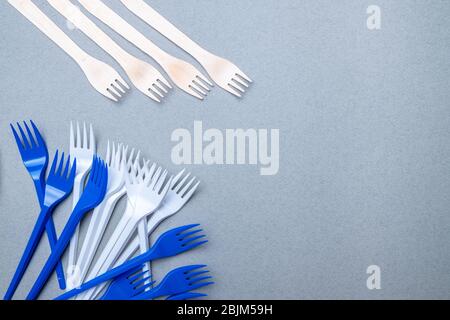 Gabeln aus Holz und Kunststoff auf grauem Hintergrund. Flaches Lay. Kopierbereich. Das Konzept der Umweltverschmutzung durch schwer abbaubare Abfälle. Stockfoto