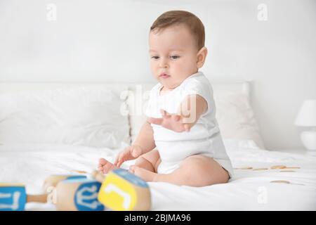 Niedliches Baby, das mit Dreideln auf dem Bett spielt Stockfoto