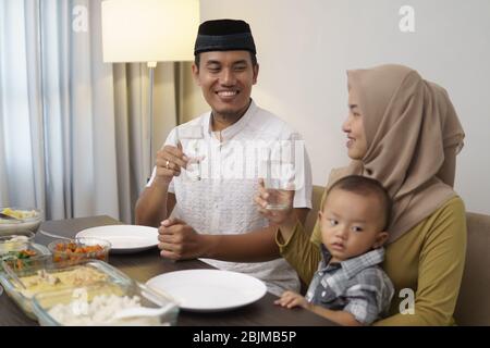 die muslimische asiatische Familie trinkt ein Glas Wasser, um abends das Fasten zu brechen Stockfoto