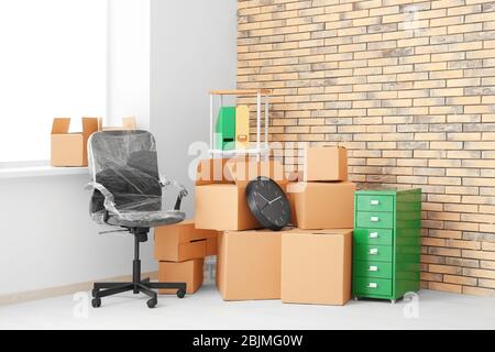 Office Move Konzept. Kartons und Möbel in leerem Raum Stockfoto