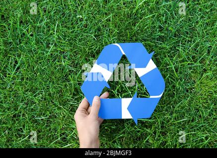 Frau, die das Symbol des Recyclings gegen grünes Gras hält Stockfoto