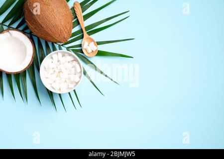 Flache Lay Zusammensetzung mit Kokosnuss und tropischen Palmblatt auf blauem Hintergrund. Konzept der gesunden Ernährung oder Bio-SPA kosmetische Zutaten. Sommer-Bac Stockfoto