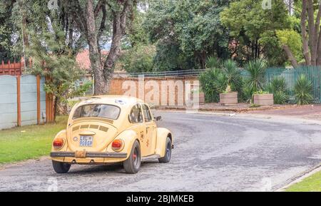Alberton, Südafrika - ein funky Retro-gelben Volkswagen Beetle mit Blumen Aufkleber auf ihm isoliert Fahren in einer Nachbarschaft Straße stecken Stockfoto