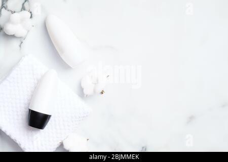 Deodorant Flaschen mit Baumwollblumen auf Marmor Hintergrund. Flach liegend, Draufsicht. Weiße Antitranspirant Verpackung, Schweißschutz Produktkonzept Stockfoto