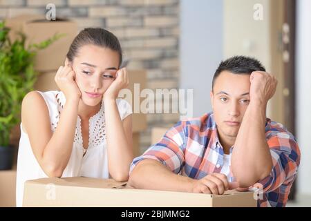 Müde junges Paar mit Umzugsbox in ihrer neuen Wohnung Stockfoto