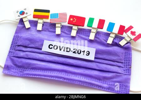 Coronavirus in der Welt,. Flagge der Länder auf der Gesichtsmaske für Virus mit den Worten Coronavirus COVID-19 Stockfoto