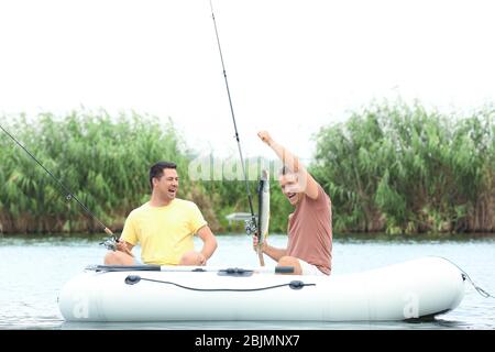 Zwei Männer fischen von Schlauchboot auf Fluss Stockfoto