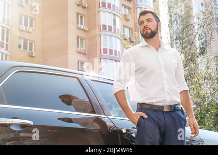 Schöner junger Mann in weißem Hemd in der Nähe von Auto im Freien stehen Stockfoto