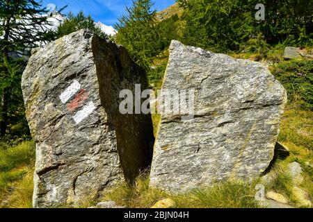 Rot-weiße Wanderzeichen auf Stein in den Schweizer Alpen. Stockfoto