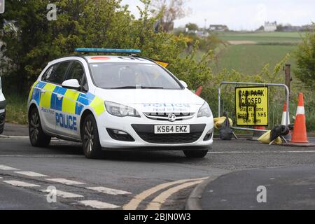 Ein Polizeiauto blockiert die Straße, auf der ein Hakenkreuz auf ein Schild am Eingang zu einer geschlossenen Straße und Parkplatz in der Nähe des Leuchtturms Whitley Bay, Northumberland, gesprüht wurde. Auf den Schildern an mehreren Parkplätzen entlang der Küstenstraße Northumberland sind Graffiti zu sehen, während Großbritannien weiterhin gesperrt wird, um die Ausbreitung des Coronavirus einzudämmen. Stockfoto