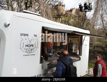 Ritchie Roncero von der Wohltätigkeitsorganisation Step to Hope in Edinburgh gibt Mahlzeiten an Obdachlose in der Pfarrkirche St. Cuthbert in Edinburgh aus. Normalerweise werden Mahlzeiten in der Kirche serviert, aber aufgrund von Einschränkungen werden diese außerhalb an die Obdachlosen übergeben, da das Vereinigte Königreich weiterhin in der Sperre, um die Ausbreitung des Coronavirus einzudämmen. Stockfoto