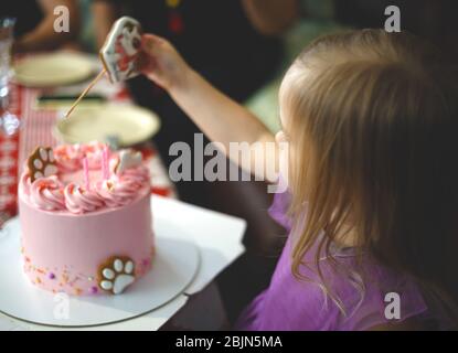 Kleines Mädchen in Lavendel Kleid bereitet sich auf die Luft blasen Kerzen auf einem Urlaub Kuchen. Stockfoto