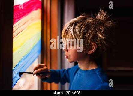 Junge Malerei einen Regenbogen auf einem Fenster, USA Stockfoto