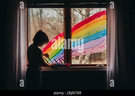 Junge Malerei einen Regenbogen auf einem Fenster, USA Stockfoto