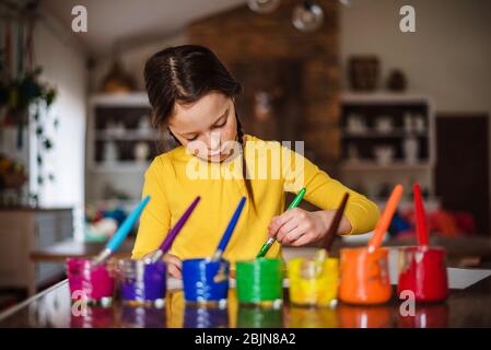 Mädchen sitzt in der Küche Malerei einen Regenbogen Stockfoto