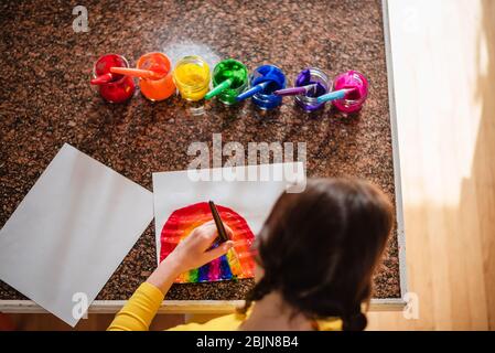 Mädchen sitzt in der Küche Malerei einen Regenbogen Stockfoto