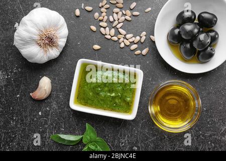 Zusammensetzung mit Schüssel mit köstlichen Basilikum Pesto Sauce auf grauem Hintergrund Stockfoto