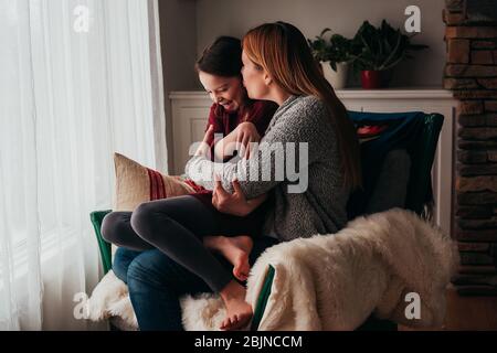 Mutter und Tochter kuscheln in einem Sessel Stockfoto