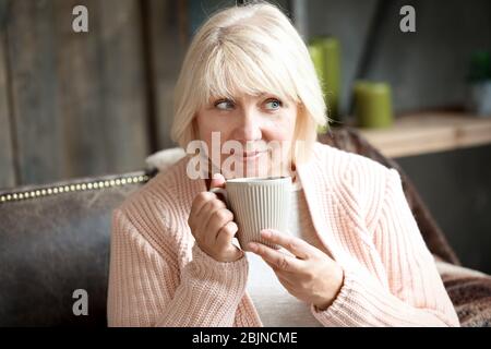 Wunderschöne reife Frau trinkt Kaffee zu Hause Stockfoto