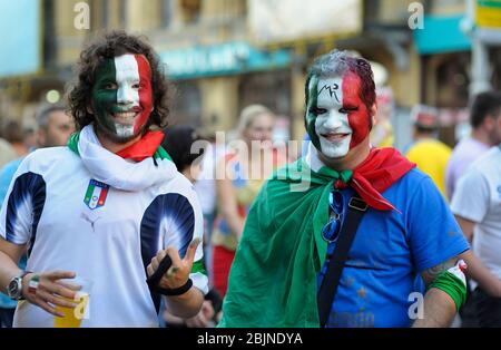 Zwei italienische Fußballfans, Gesichter in Nationalfarben bemalt, halten Daumen hoch jubeln für ihre Fußballmannschaft Stockfoto