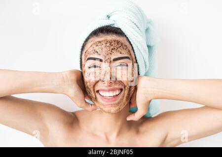 Junge lächelnde Frau Anwendung Kaffee Peeling Maske auf Gesicht - Happy girl mit Hautpflege Spa Tag zu Hause Stockfoto