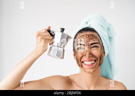 Junge lächelnde Frau Anwendung Kaffee Peeling Maske auf Gesicht - Happy girl mit gesunden Hautpflege Spa Tag zu Hause Stockfoto
