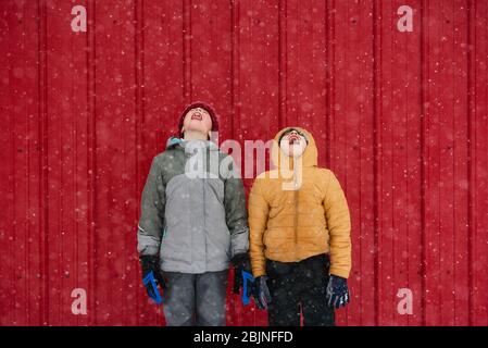 Zwei Kinder fangen Schneeflocken im Mund, USA Stockfoto