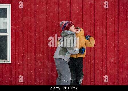Zwei Kinder fangen Schneeflocken im Mund, USA Stockfoto