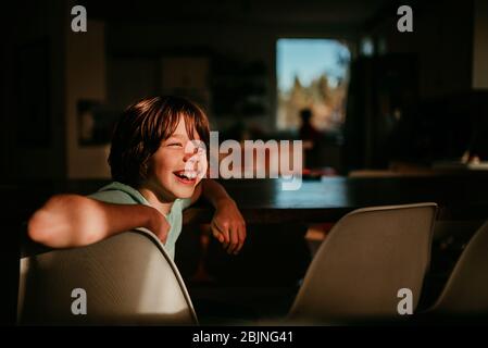 Happy Boy sitzt an einem Esstisch Stockfoto