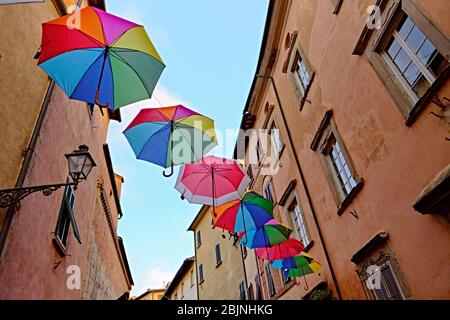 Reihe von bunten Sonnenschirmen auf einer städtischen Straße zwischen alten Stadthäuser bis auf der Suche nach einem blauen Himmel hängenden Stockfoto