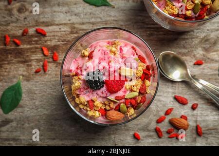 Köstliches Dessert mit Goji Beeren im Glas auf Holzhintergrund Stockfoto