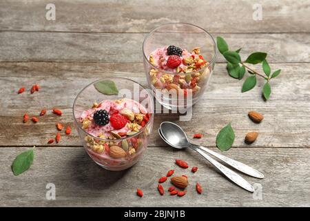 Köstliches Dessert mit Goji Beeren in Gläsern auf Holzhintergrund Stockfoto