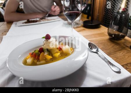 Köstliches Dessert in einem Restaurant, Valencia, Spanien. Gastronomische Küche, schöne Präsentation. Frisches Obst und Eis mit einem Mangocoulis. Stockfoto