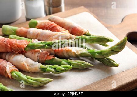 Teller mit Speck umwickelt Spargel auf hellem Hintergrund Stockfoto
