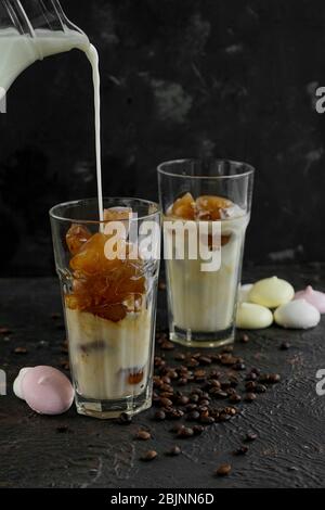 Gefrorener, gebrauter Kaffee in Eiswürfeln auf einem dunklen, strukturierten Hintergrund in Glasgläsern Stockfoto