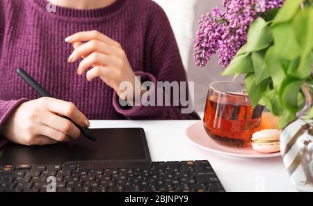 Graphic Designer Retucher Freelancer arbeitet von zu Hause aus. Frau nutzt Grafik-Tablet im Home Office mit Laptop und Computer. Remote-Arbeit in gemütlichen Stockfoto