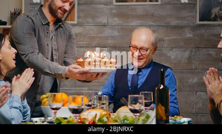 Älterer Mann feiert seinen Geburtstag mit der Familie. Leckerer Kuchen. Zeitlupe aufgenommen Stockfoto