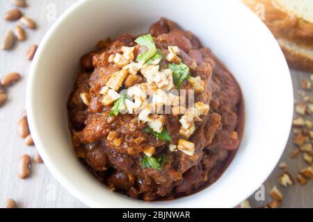 Traditionelle georgische vegane Nierenträger Eintopf lobio mit gehackten Walnüssen und Petersilie in einer Schüssel mit Scheiben Brot serviert Stockfoto