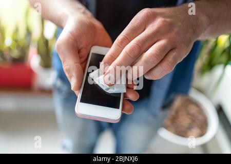 Mann, der ein Desinfektionswischtuch auf einem Telefon verwendet Stockfoto
