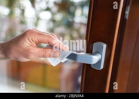 Außenhandtücher, die den Türgriff mit einem Desinfektionsmittel abwischen Stockfoto