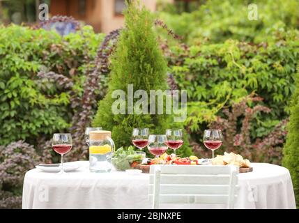 Essen und Wein serviert auf dem Tisch für Grillparty im Garten Stockfoto