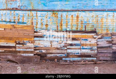 Außen eine vertäfelte, alte Holzwand mit heruntergekommenen Gemälden am Sandstrand Stockfoto
